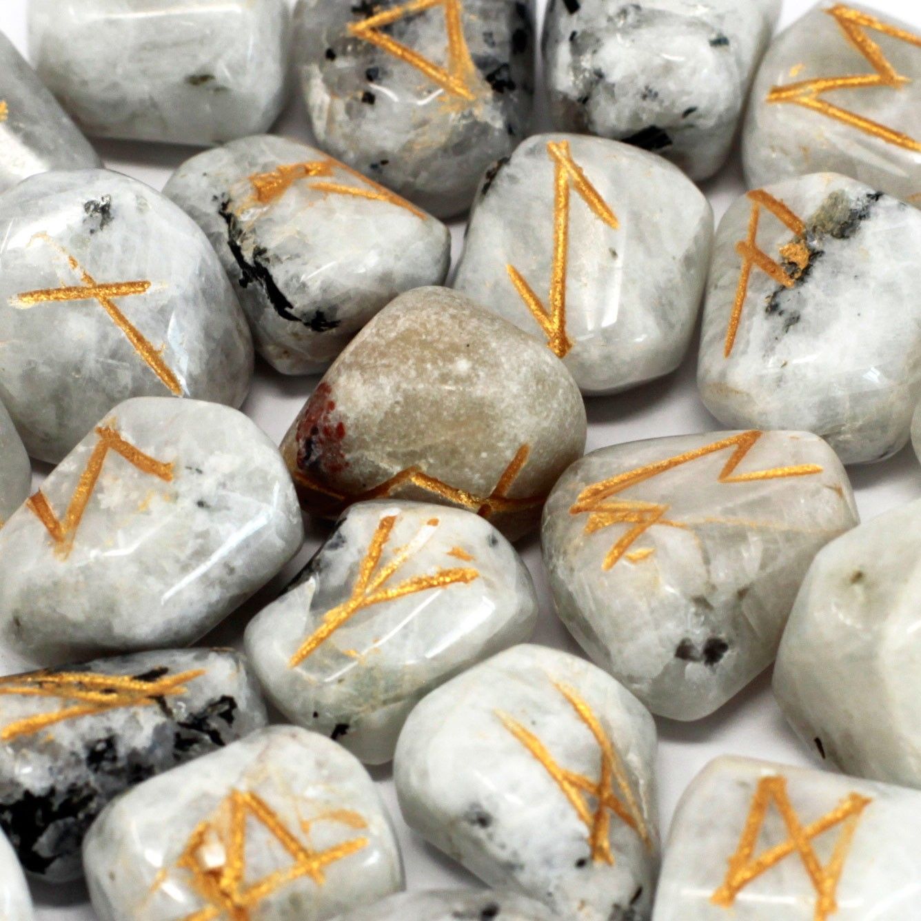 A set of rainbow moonstone rune stones with gold symbols.