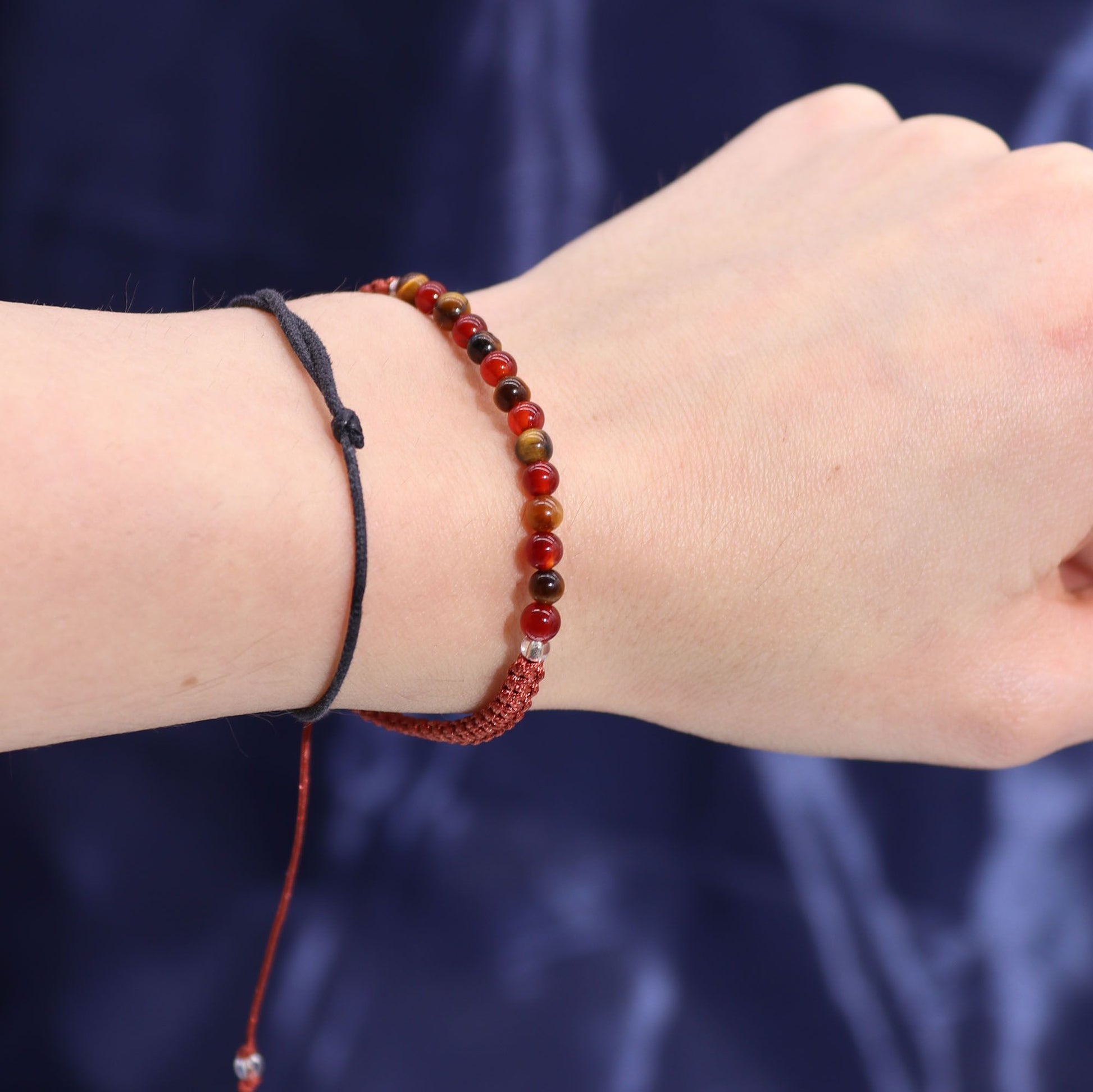 Armband mit Tigerauge- und Karneolperlen und einem roten geflochtenen Band.