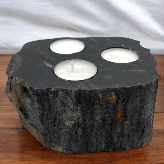 Versteinerter Holz-Teelichthalter mit drei Kerzen.