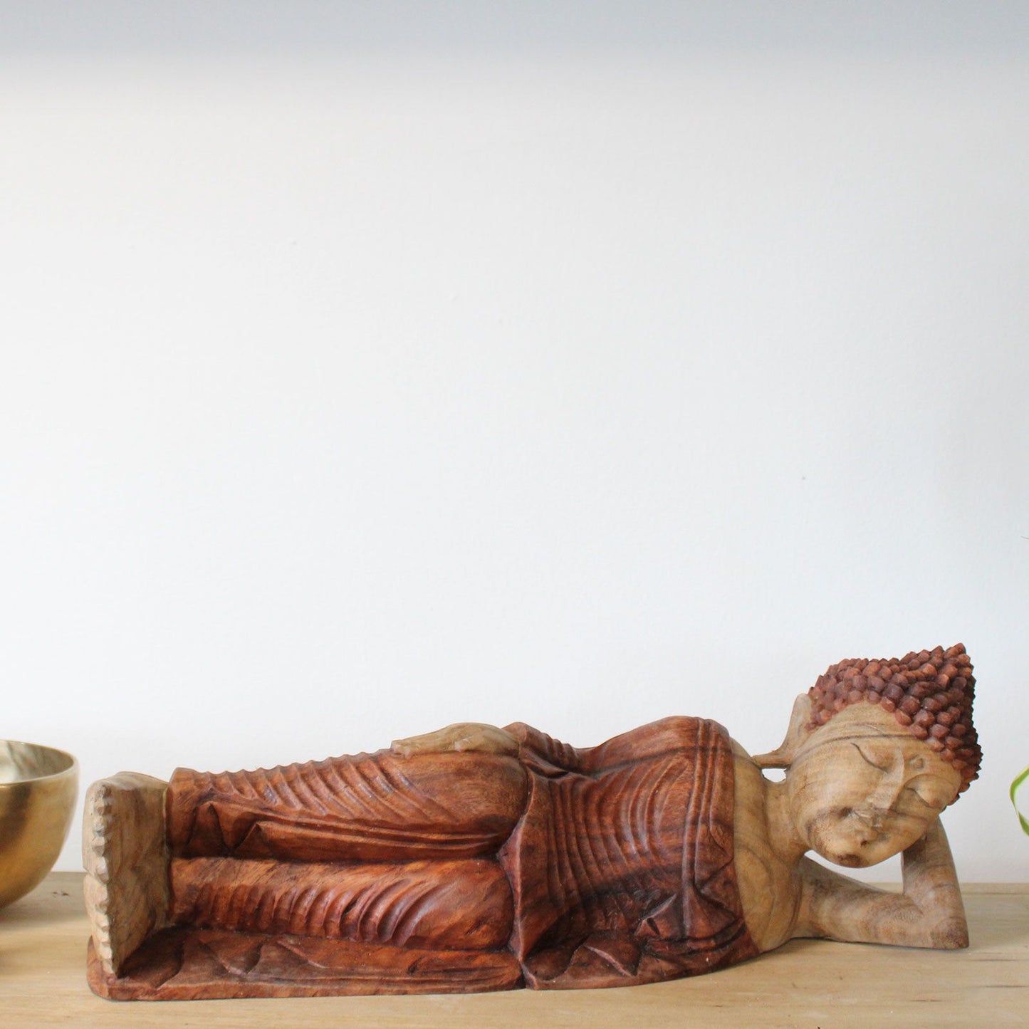 Hand carved wooden sleeping Buddha statue with intricate details.