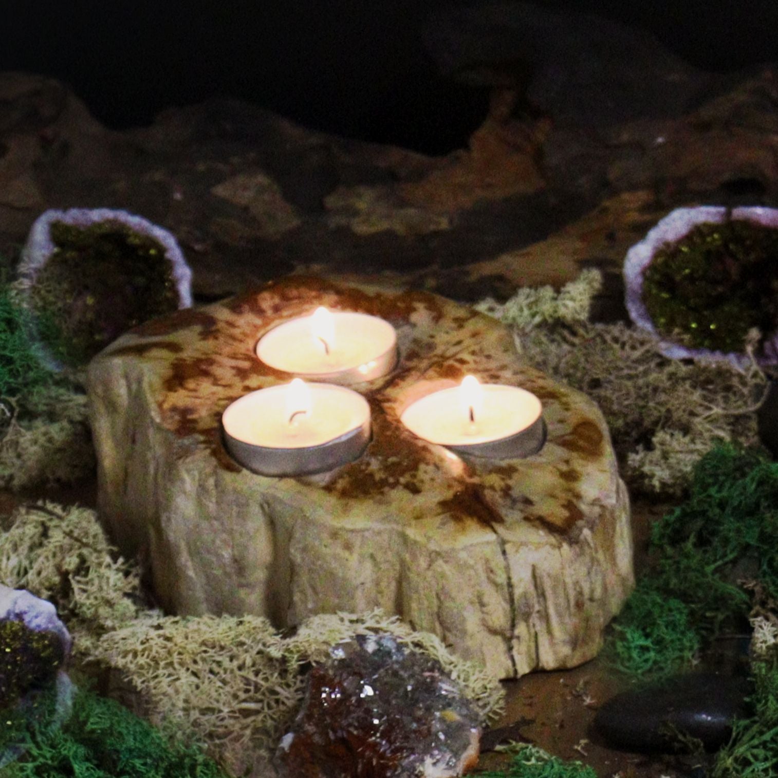 Versteinertes Holz Teelichthalter mit drei Kerzen auf Moos und Kristallen.