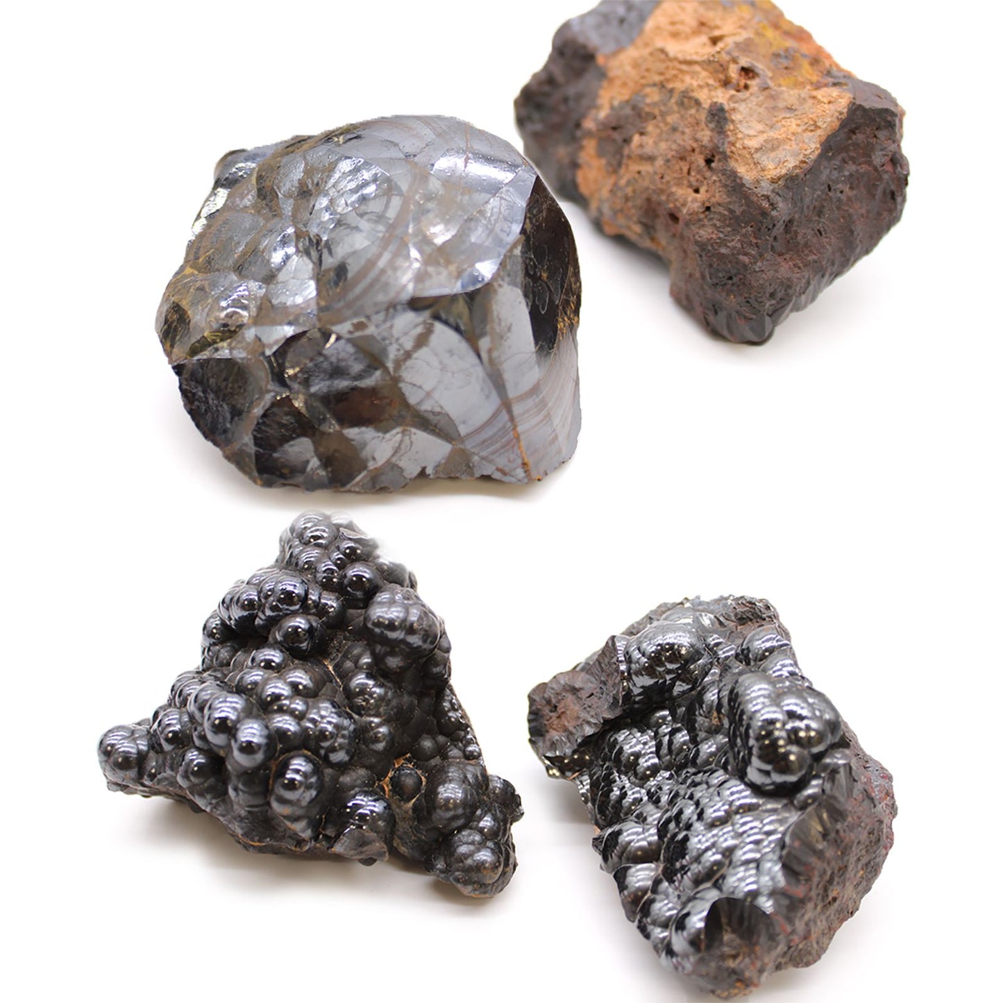 Vier rohe Hämatit-Steine mit metallischem Glanz auf weißem Hintergrund.