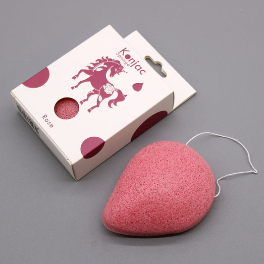 Teardrop-shaped pink konjac sponge with a white hanging string, next to its rose-themed packaging.