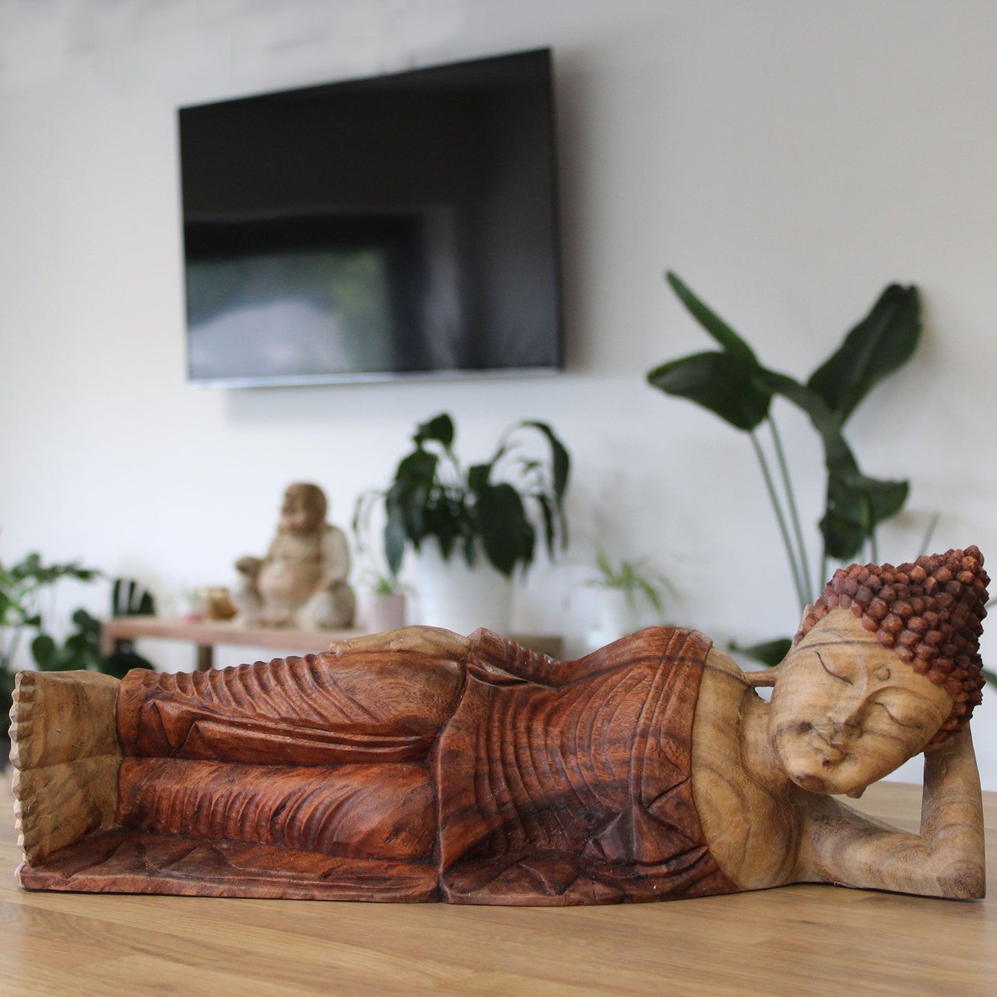 Hand carved wooden sleeping Buddha statue on a wooden surface.