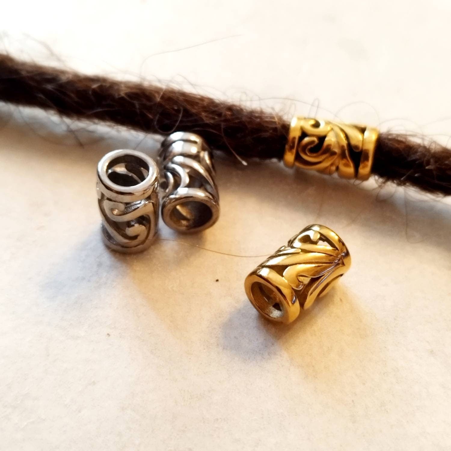 Zwei Edelstahl-Dreadperlen mit filigranem Muster.