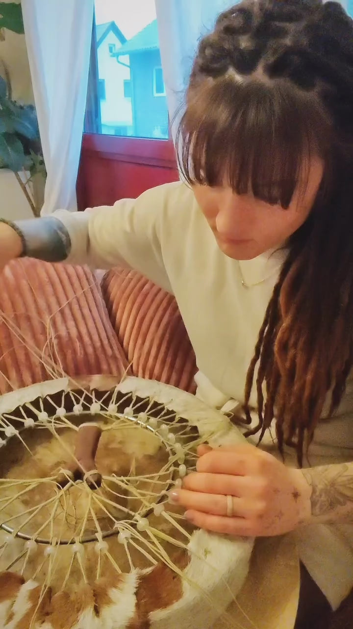 Load video: In diesem Video bekommst du einen Einblick in meine Handarbeit als Trommelbauerin: Ich schnüre das Motiv des „Baum des Lebens“ um den Griff einer schamanischen Trommel – mit viel Achtsamkeit, spiritueller Verbindung und Liebe zum Detail. Jede meiner Trommeln ist ein handgefertigtes Unikat, das in einem intuitiven Prozess entsteht. Die Schnürung symbolisiert nicht nur Stabilität, sondern auch die tiefe Verwurzelung und Verbindung zwischen Himmel und Erde.Entdecke, wie aus einfachen Materialien ein kraftvolles Ritualinstrument entsteht – Schritt für Schritt, mit Herz und Seele.